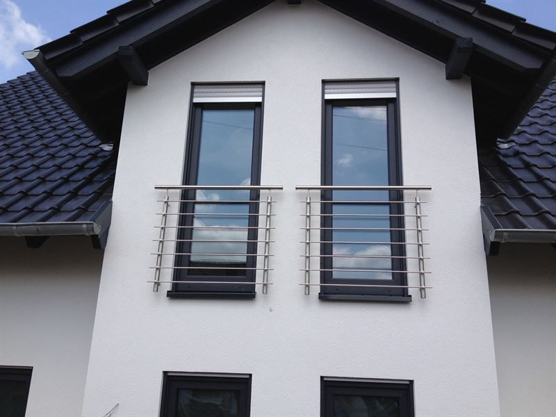 Ein weißes Haus mit schwarzen Fenstern und einem Balkon