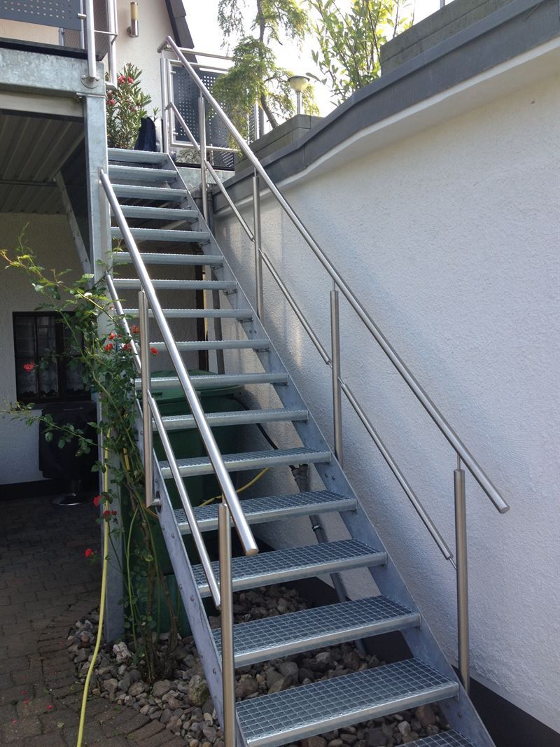 Eine Treppe mit Edelstahlgeländer, die zu einem Balkon führt.