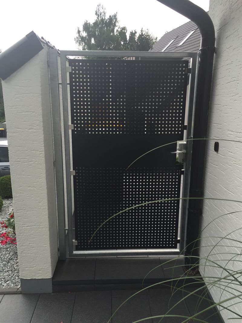 An der Seite eines Gebäudes befindet sich ein schwarzes Tor