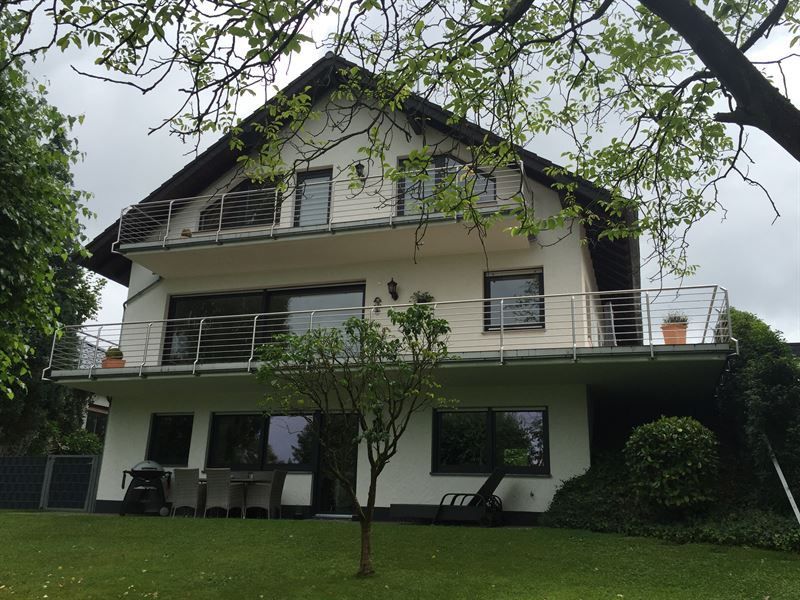 Ein weißes Haus mit einem Balkon und einem Baum davor