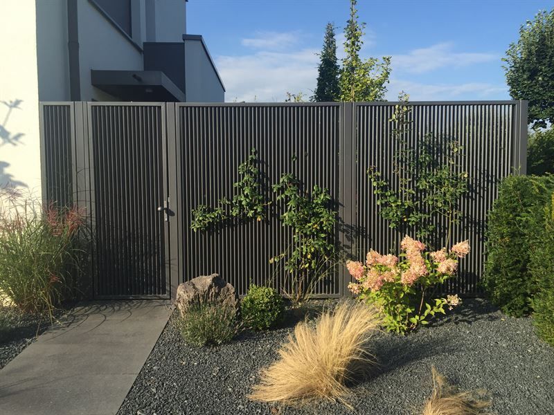 Ein Zaun mit einem Tor und Blumen vor einem Haus.