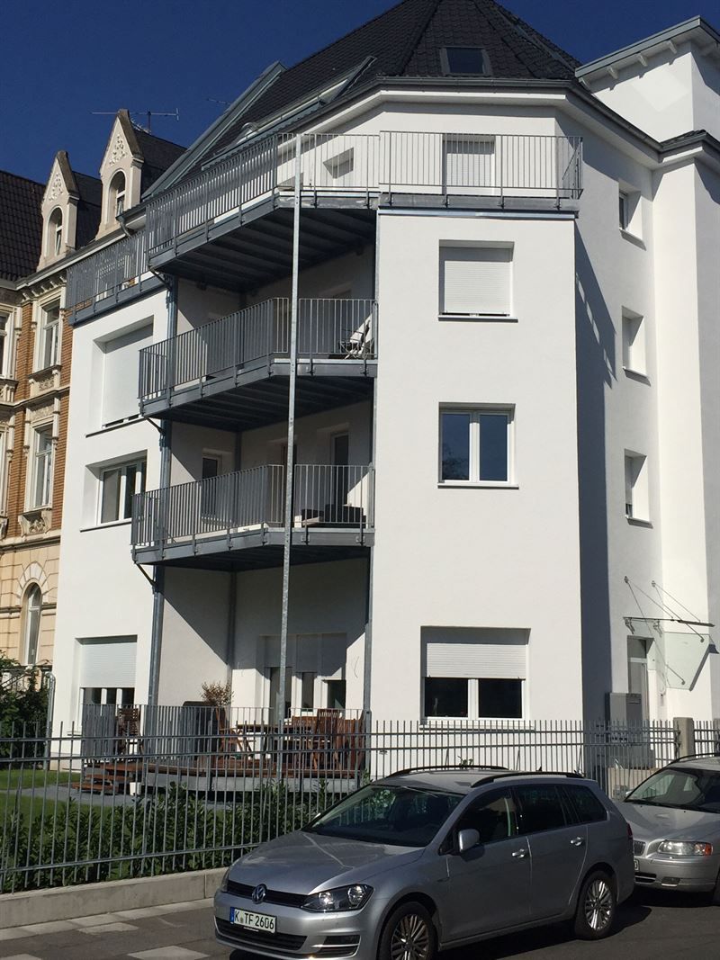 Ein silbernes Auto steht vor einem weißen Gebäude