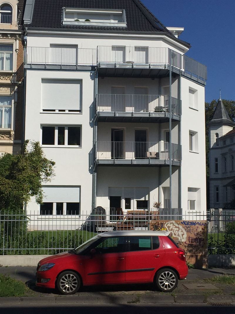 Ein rotes Auto steht vor einem weißen Gebäude