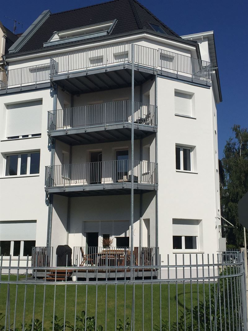 Ein großes weißes Gebäude mit Balkonen und einem Zaun darum