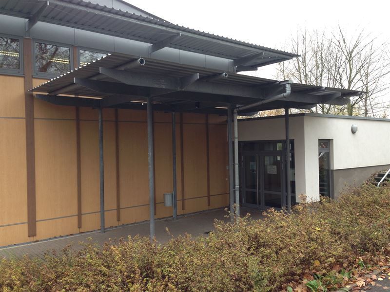 Ein Gebäude, zu dem ein überdachter Gehweg führt