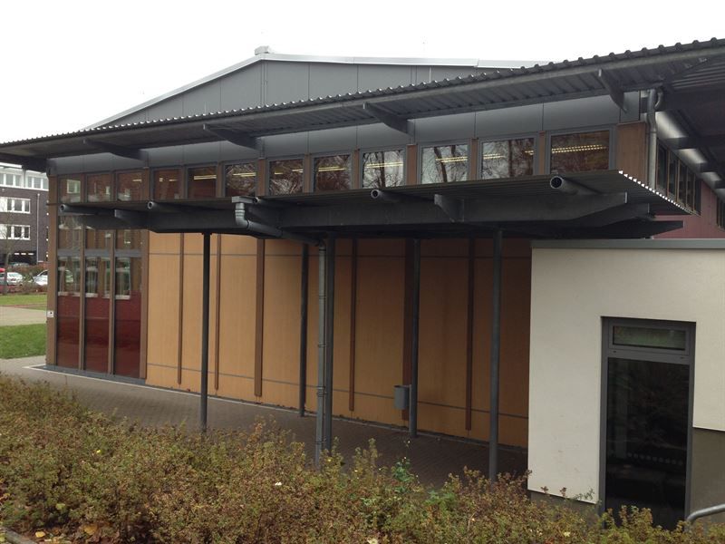 Ein großes Gebäude, zu dem ein überdachter Gehweg führt