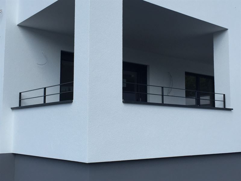 Ein weißes Gebäude mit Balkon und schwarzem Geländer