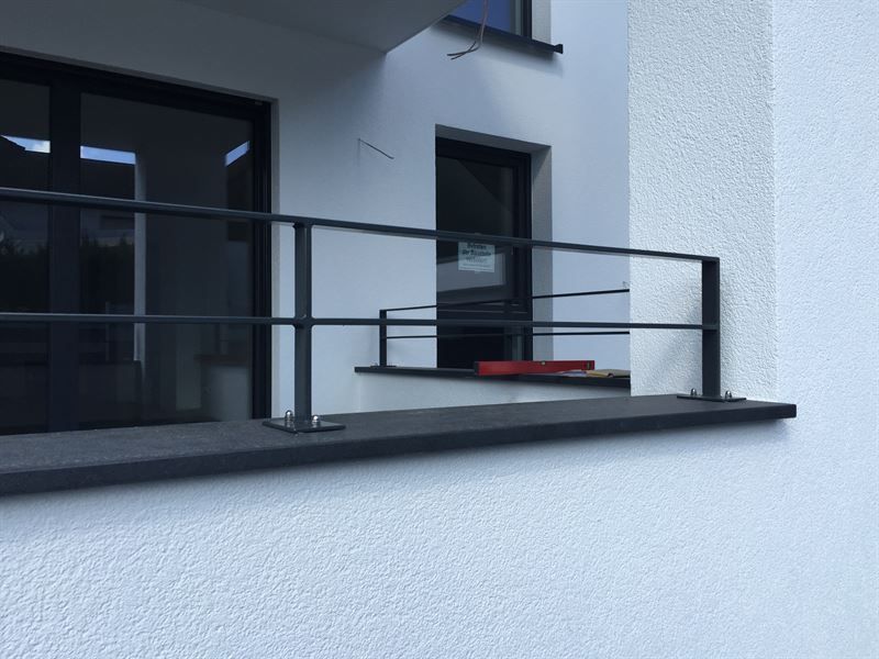 Ein Balkon mit schwarzem Geländer an einem weißen Gebäude