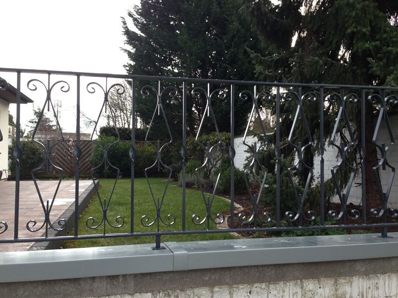 Ein schmiedeeiserner Zaun umgibt einen üppigen grünen Hof