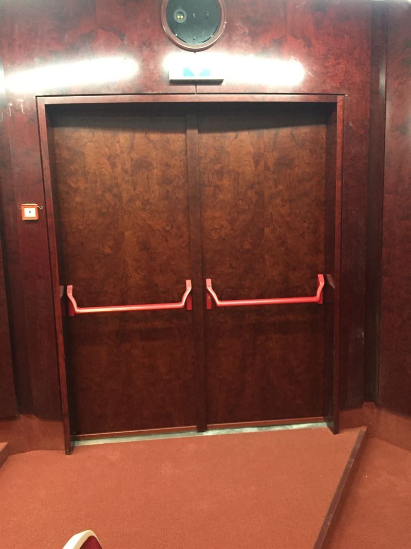 Ein Paar Holztüren mit roten Griffen in einem Raum.