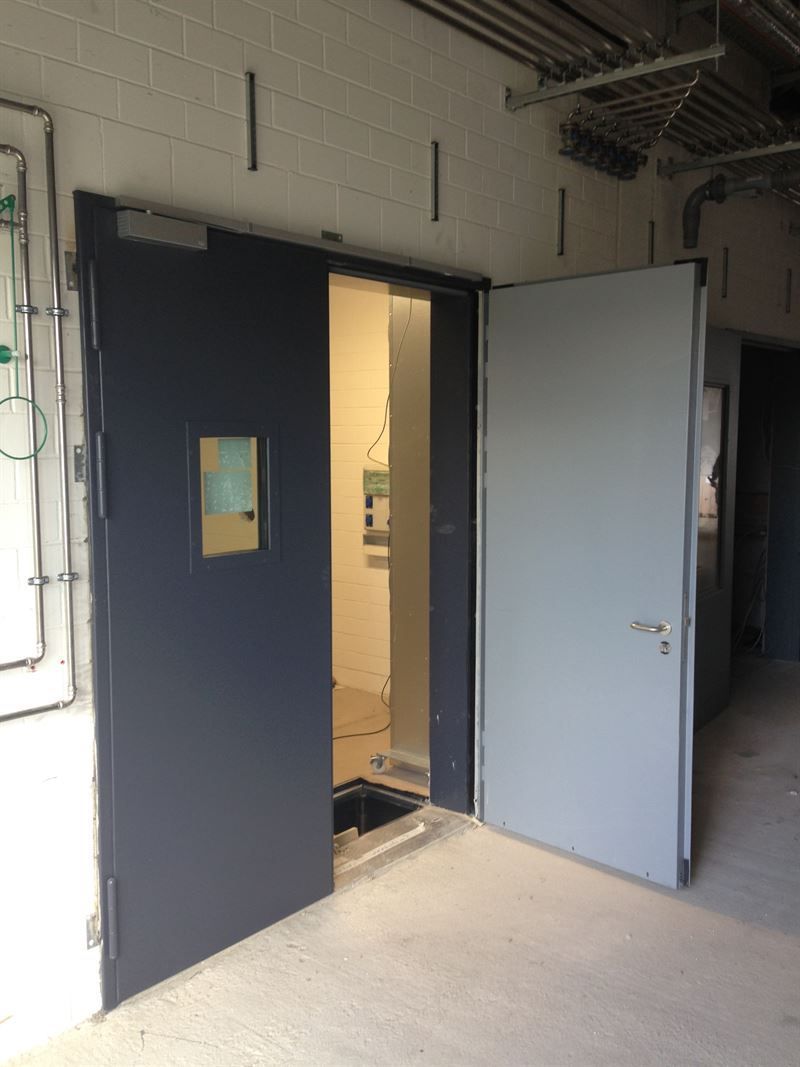 In einem Raum steht eine Tür mit einem kleinen Fenster offen