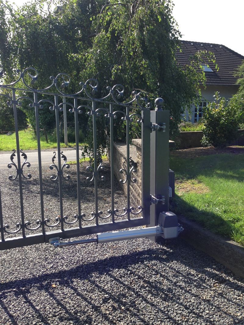 Vor einem Haus ist ein Tor mit angeschlossenem Motor geöffnet.