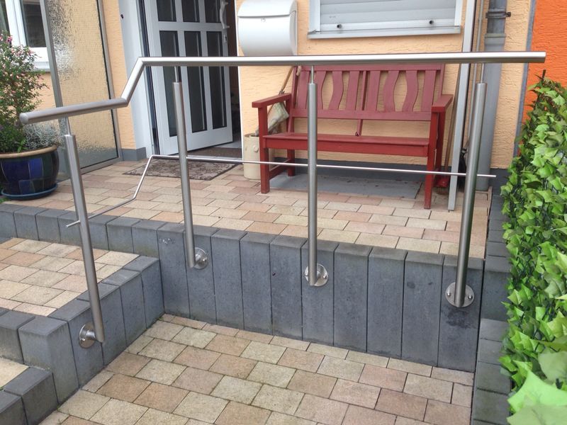 Ein Edelstahlgeländer mit einer Bank im Hintergrund