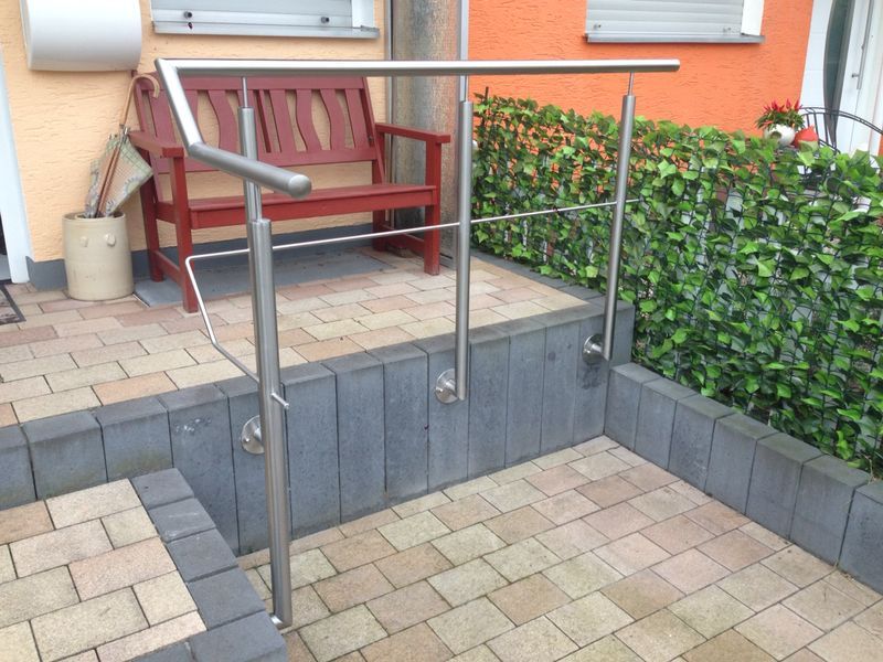 Ein Edelstahlgeländer mit einer Bank im Hintergrund