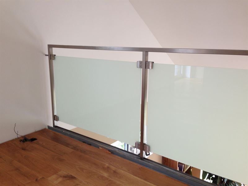 Ein Balkon mit Glasgeländer und Holzboden