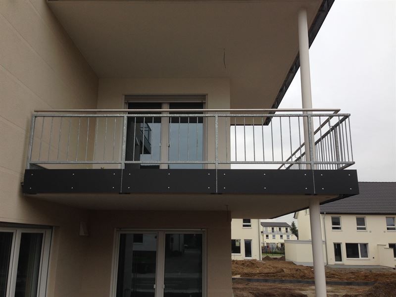 Ein Balkon an der Seite eines Gebäudes mit einem Edelstahlgeländer