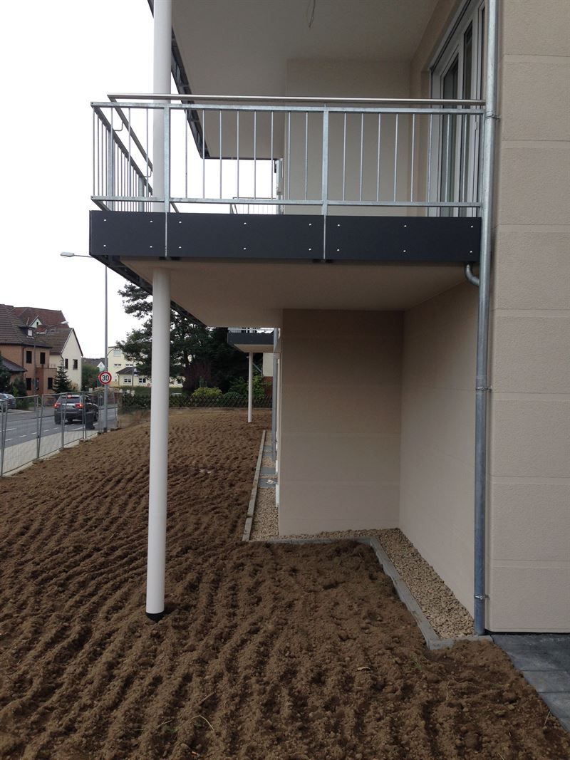 Ein Balkon an der Seite eines Gebäudes neben einem Feld.