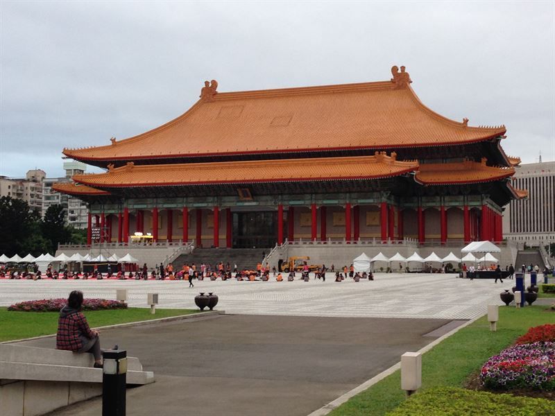 Eine Frau sitzt auf einer Bank vor einem großen Gebäude