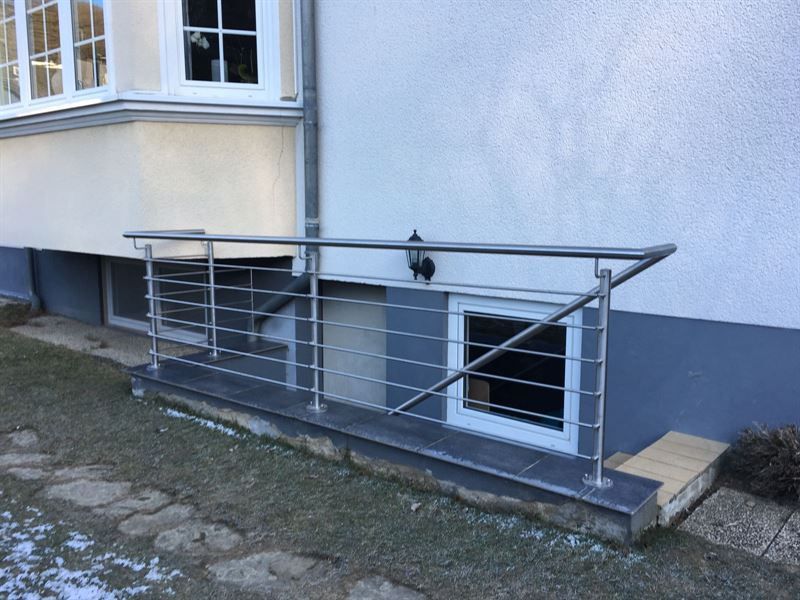 An der Seite eines Gebäudes wird ein Edelstahlgeländer angebracht.