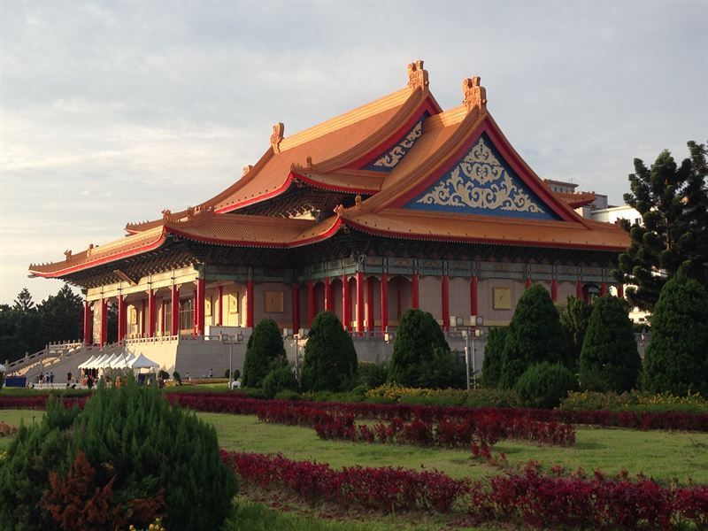 Ein großes Gebäude mit einem roten Dach ist von Bäumen und Büschen umgeben