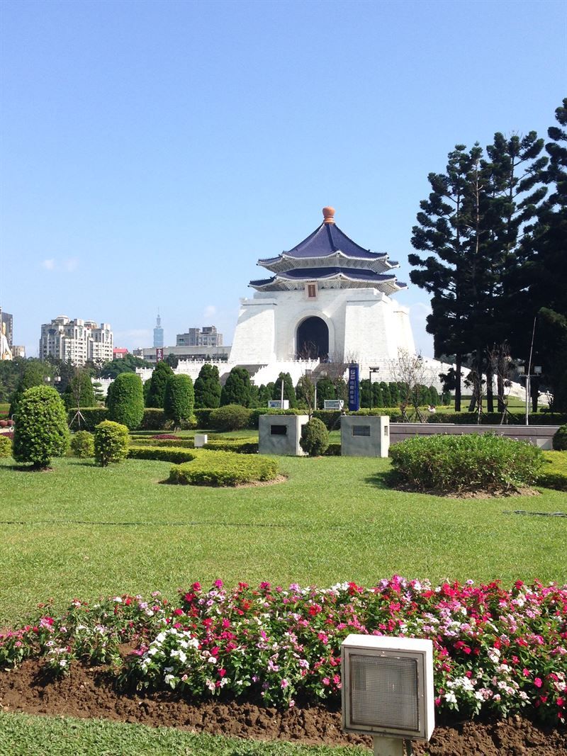 Ein großes weißes Gebäude steht inmitten eines von Blumen umgebenen Parks.