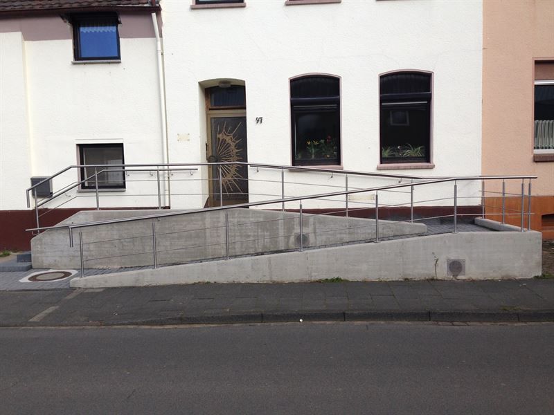 Eine Rampe, die zu einem Haus mit einem Geländer führt
