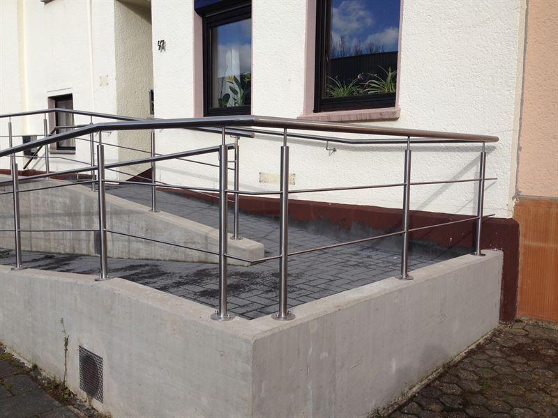 Ein Edelstahlgeländer mit Rampe vor einem Gebäude