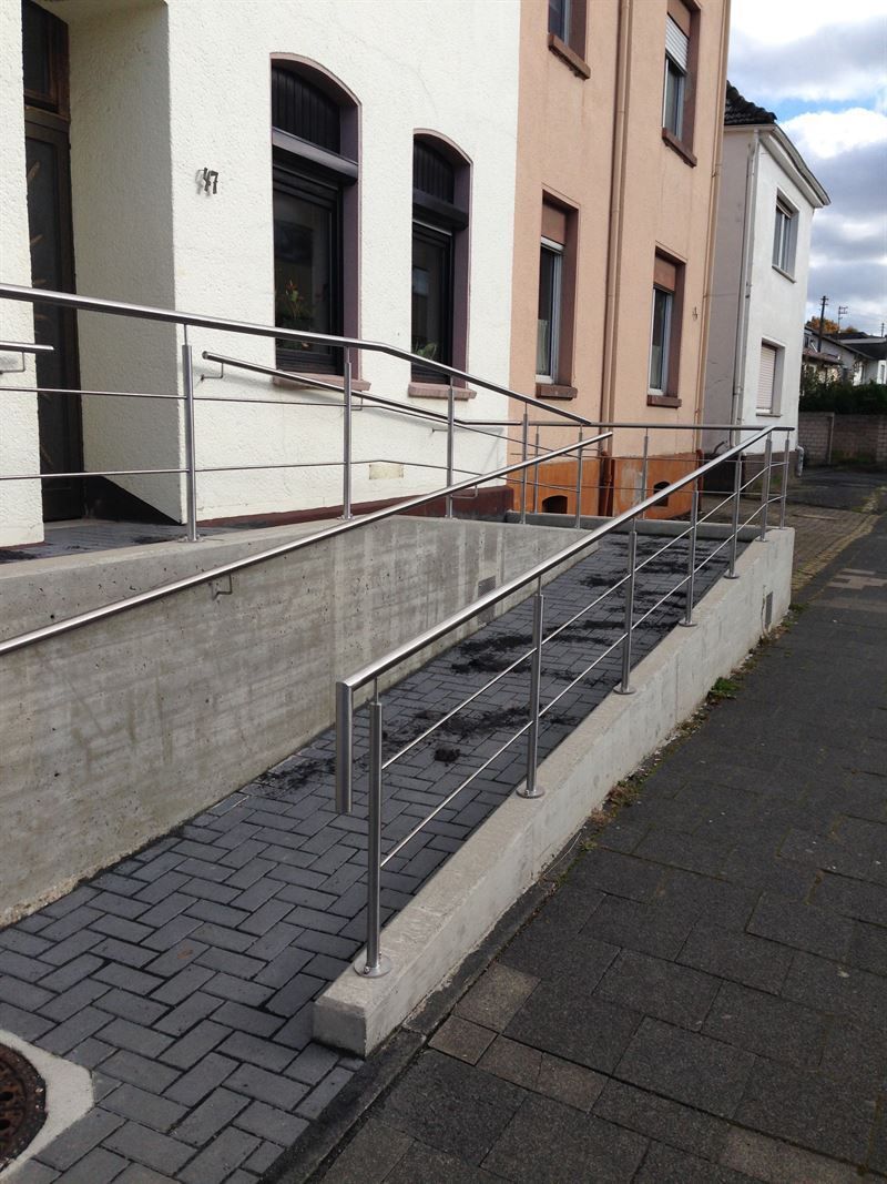 Eine Rampe, die zu einem Gebäude mit einem Edelstahlgeländer führt