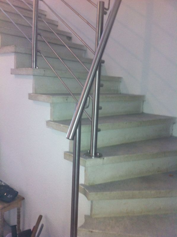 Eine Treppe mit einem Edelstahlgeländer in einem Raum.