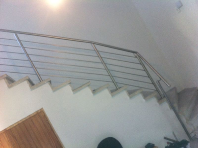 Eine Treppe mit einem Edelstahlgeländer in einem Raum.