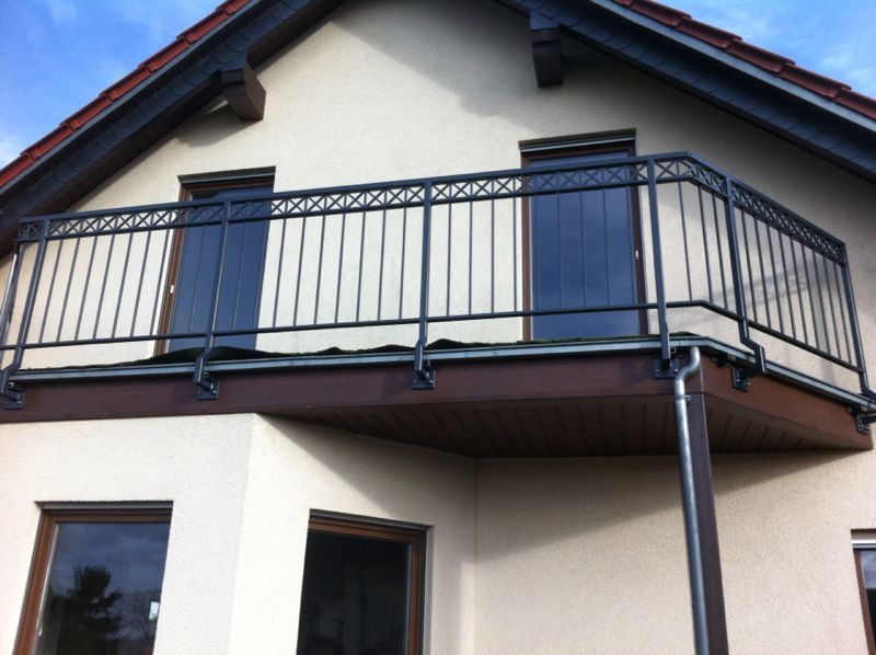 Ein weißes Haus mit einem Balkon mit schwarzem Geländer