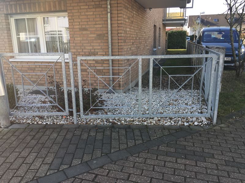 Ein Backsteingebäude mit einem Zaun und einem davor geparkten Auto.