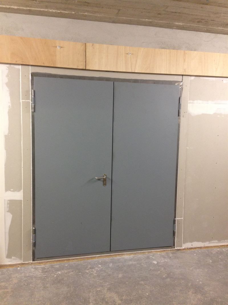 Ein Paar graue Türen in einem Raum mit einem Holzrahmen.