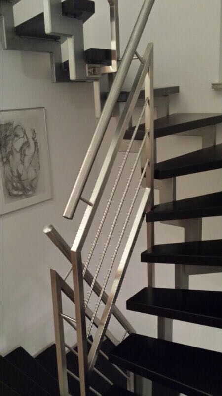Eine Treppe mit Edelstahlgeländer und schwarzen Stufen