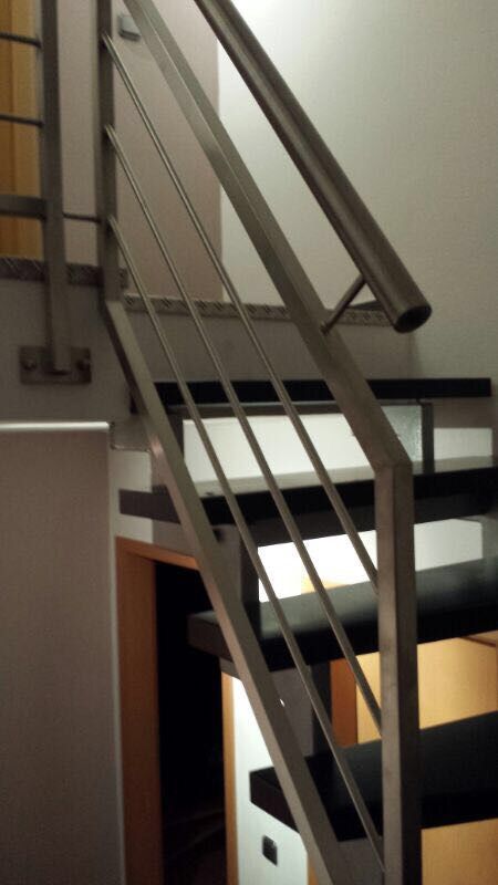 Eine Treppe mit Metallgeländer und schwarzen Stufen