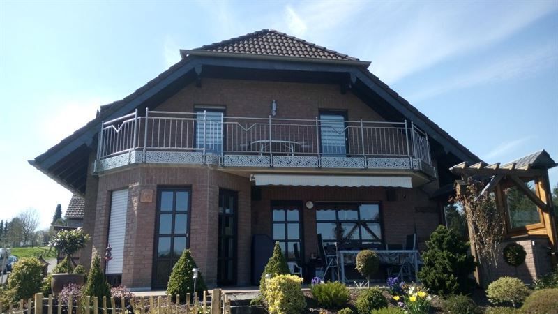 Ein großes Backsteinhaus mit Balkon und Zaun