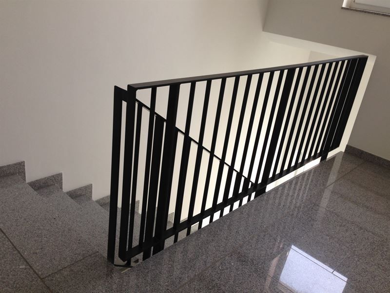 Eine Treppe mit schwarzem Geländer und weißer Wand