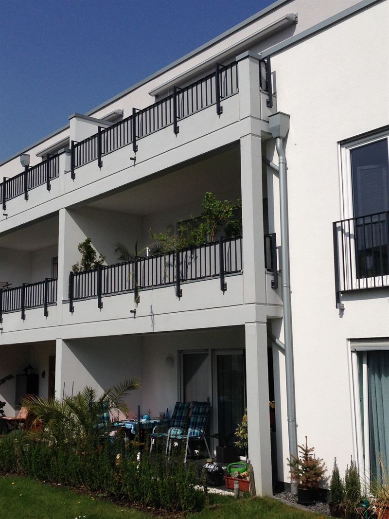 Ein weißes Gebäude mit Balkonen und einem blauen Himmel im Hintergrund