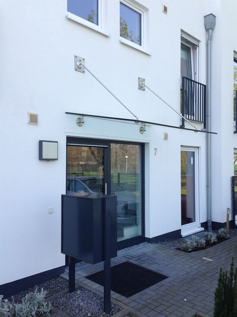 Ein weißes Gebäude mit einem Glasdach über der Tür