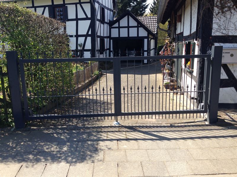 Vor einem Haus steht ein schwarzes Tor offen