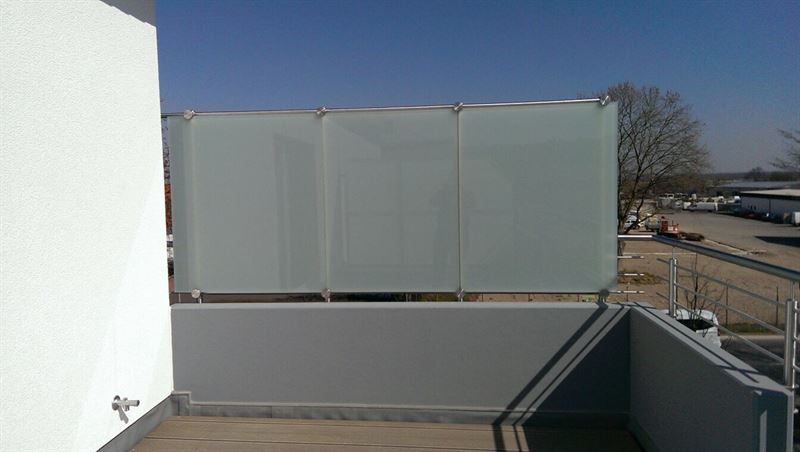 Ein Balkon mit einem Geländer aus Glas und Edelstahl.