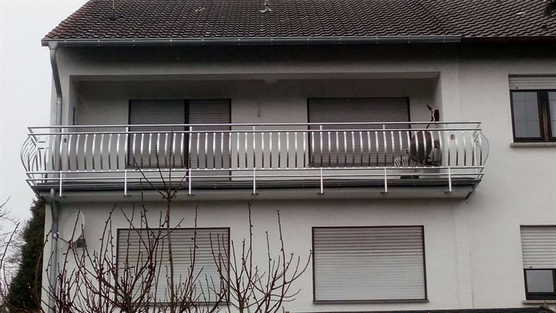 Ein weißes Haus mit einem Balkon im zweiten Stock
