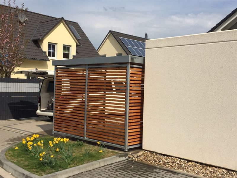 Ein Auto ist in einer Einfahrt neben einer Holzkonstruktion geparkt