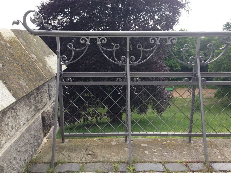 Ein schmiedeeiserner Zaun mit einem Baum im Hintergrund