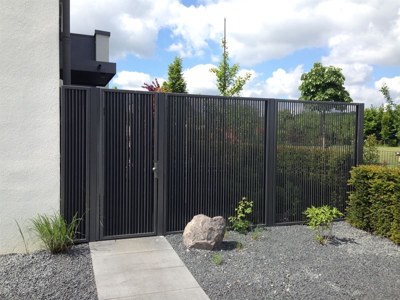 Ein Zaun mit einem Tor vor einem Haus