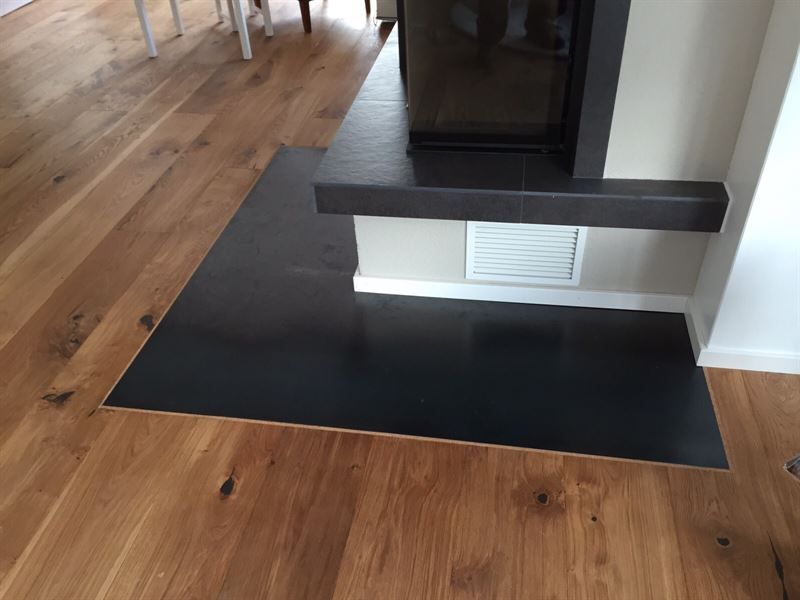 In der Mitte des Raumes befindet sich ein Kamin mit Holzboden.