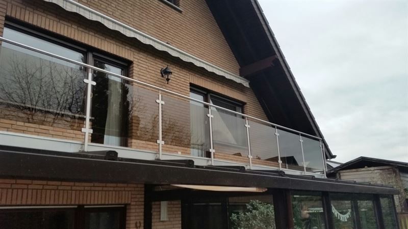 Ein Backsteinhaus mit einem Glasgeländer am Balkon.