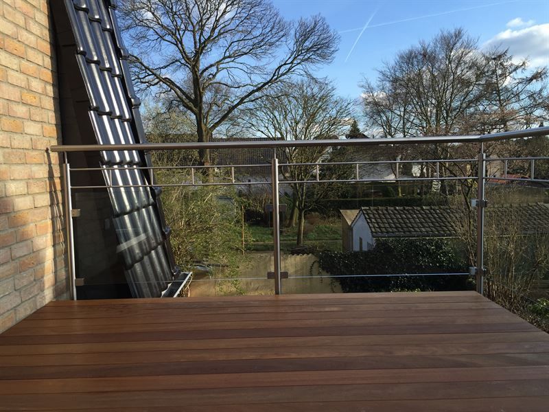 Ein Balkon mit Edelstahlgeländer und Holzterrasse.