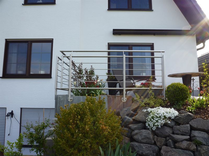 Ein weißes Haus mit einem Balkon aus Edelstahl