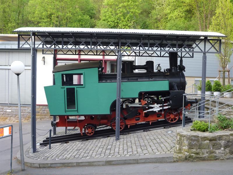 Ein grüner Zug steht unter einer Metallkonstruktion